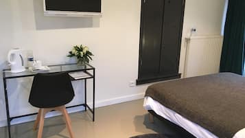 Une chambre d’hôtel comprenant un lit, un bureau avec une chaise, une télévision, une armoire et un radiateur.