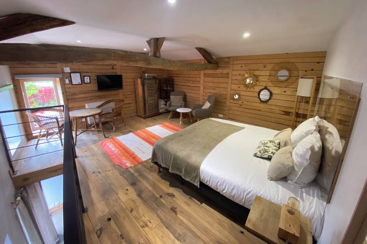 A cozy wooden cabin bedroom with a bed, a small table, and a chair.