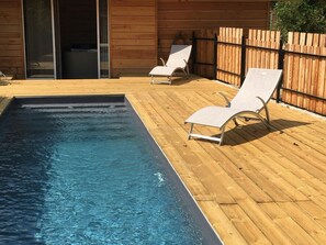 A wooden deck with a swimming pool and two lounge chairs. - O'Lodge (Cleppé)