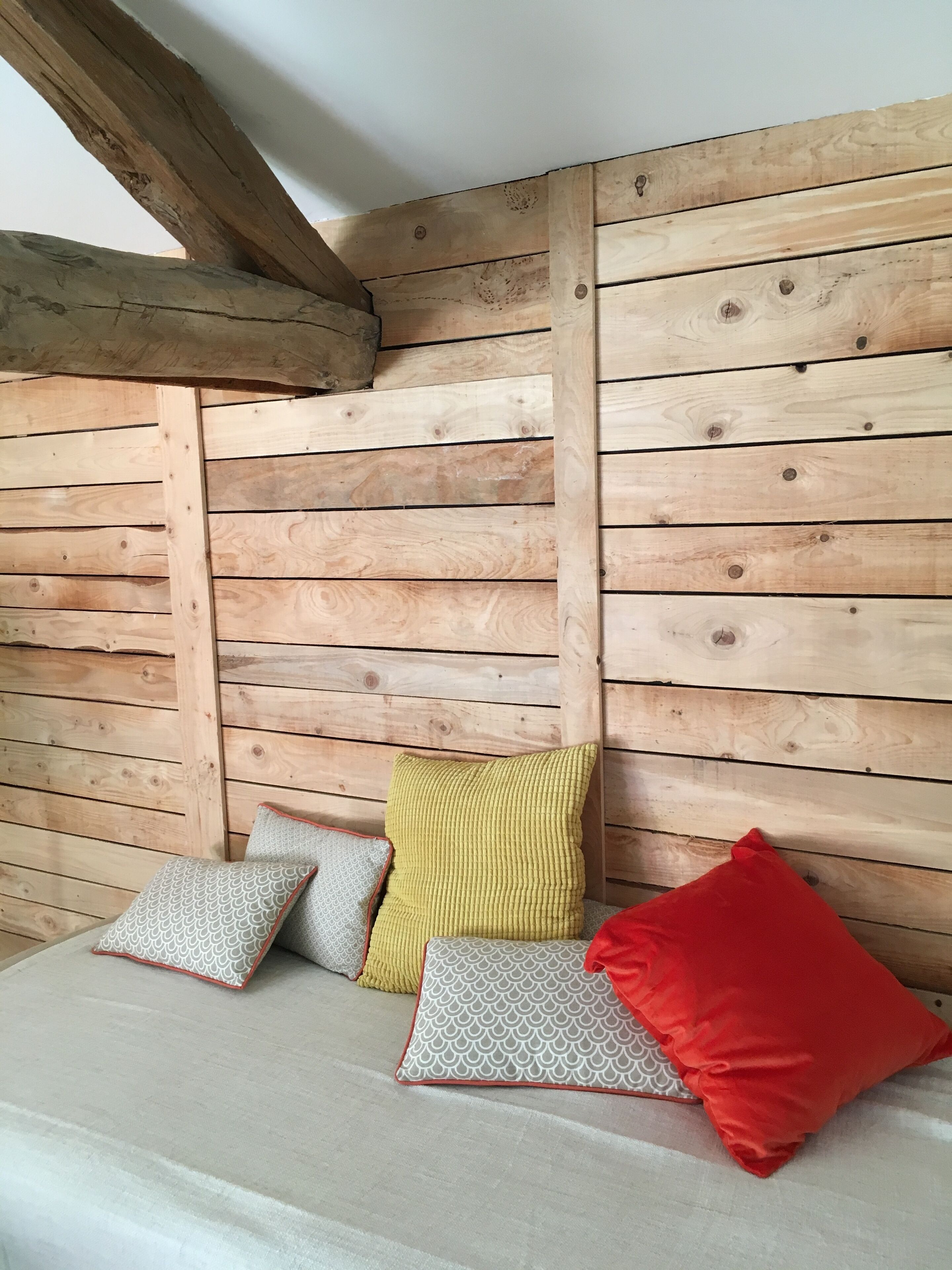 A wooden cabin interior with a bed and pillows.