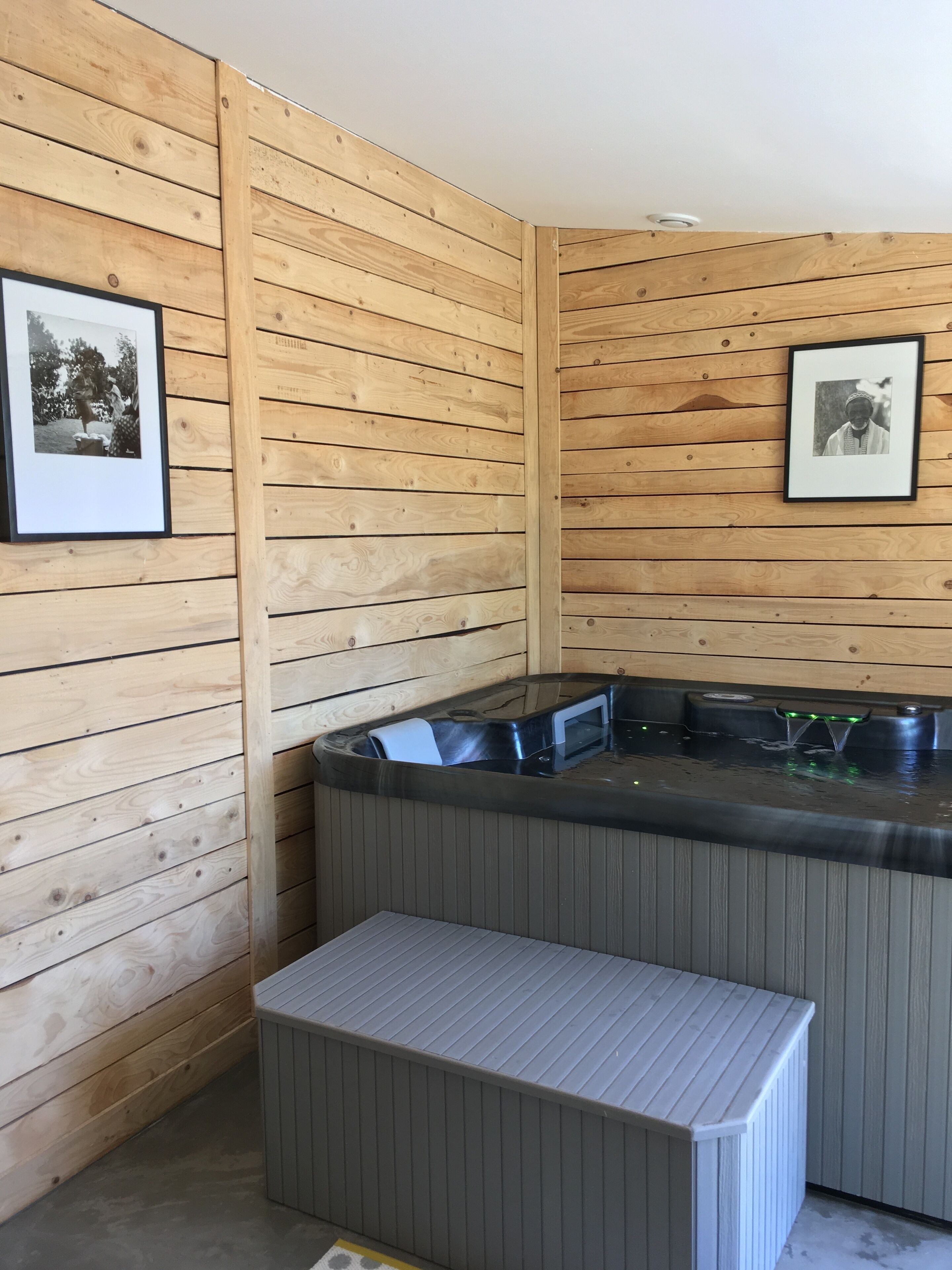 A wooden-paneled room with a hot tub and a bench.