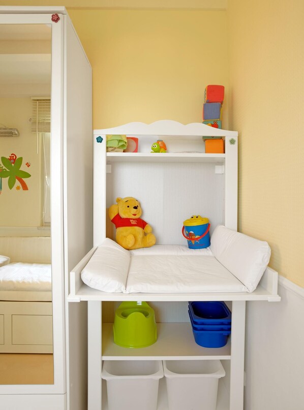 A bunk bed with a white frame, a small shelf with toys, and storage bins below. - HUS IN DE SÜNN - Peace and quiet in an idyllic setting (Insel Poel / OT Brandenhusen)