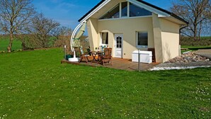 A modern house with a large deck, a dining area, and a small garden. - HUS IN DE SÜNN - Peace and quiet in an idyllic setting (Insel Poel / OT Brandenhusen)