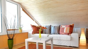 A modern living room with a sloped ceiling, white sofa, and a coffee table. - HUS IN DE SÜNN - Peace and quiet in an idyllic setting (Insel Poel / OT Brandenhusen)