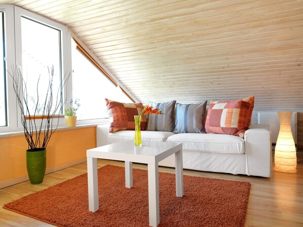 A modern living room with a sloped ceiling, white sofa, and a coffee table.