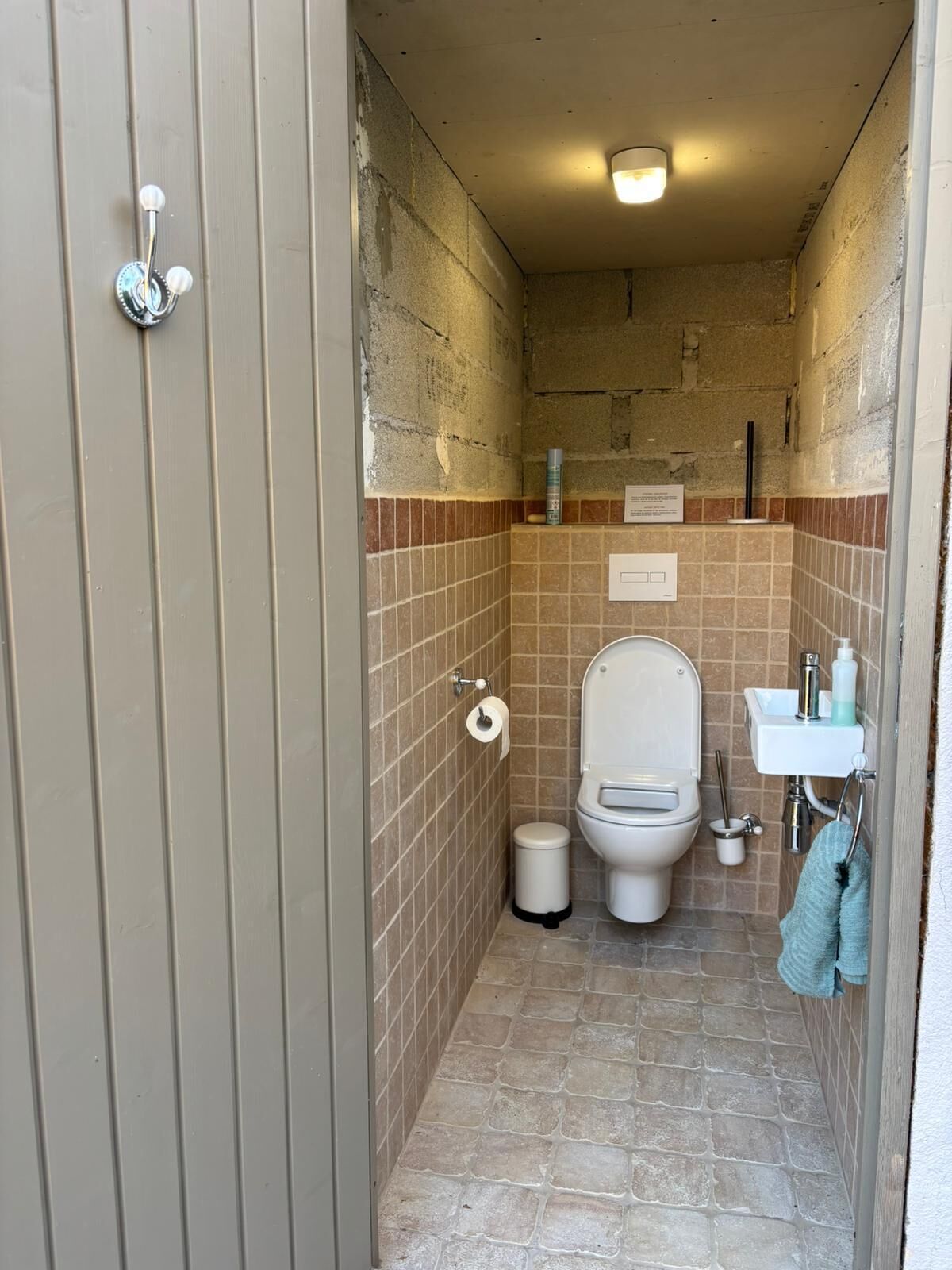 A small bathroom with a toilet, sink, and tiled walls.