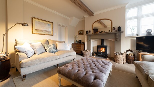 Una sala de estar acogedora con sofá, reposapiés, chimenea y televisor.