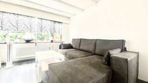 Una sala de estar moderna con un sofá seccional gris, una mesa de centro blanca y un radiador.