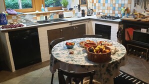 A kitchen with a dining table set for two, a dishwasher, a sink, and a stove.