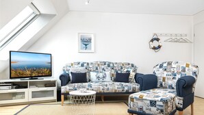 Ein modernes Wohnzimmer mit Sofa, Sessel und Couchtisch, ausgestattet mit maritimer Polsterung.