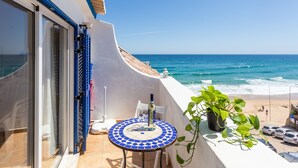A balcony with a view of the ocean, a tiled table, and a potted plant. - Casa Pedro - Burgau - Unique Converted Fisherman's Cottage (Budens)