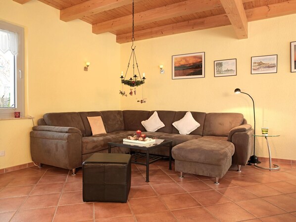 A living room with a sectional sofa, a coffee table, and a hanging light fixture.