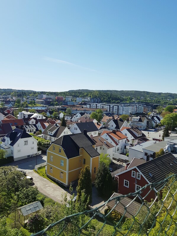 A residential area with a variety of houses, some with sloped roofs and others with flat roofs. There are trees and greenery around the houses, and a clear sky above.