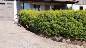 A two-story house with a tiled roof, a garage, and a covered porch. - StayPlus Central Apartment With Garden (Kristiansand)