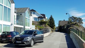A street with parked cars, modern buildings, and a clear blue sky. - StayPlus Central Apartment With Garden (Kristiansand)