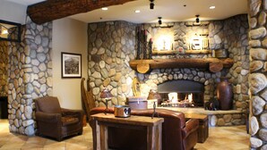 A stone-walled living room with a fireplace, leather furniture, and a wooden table.