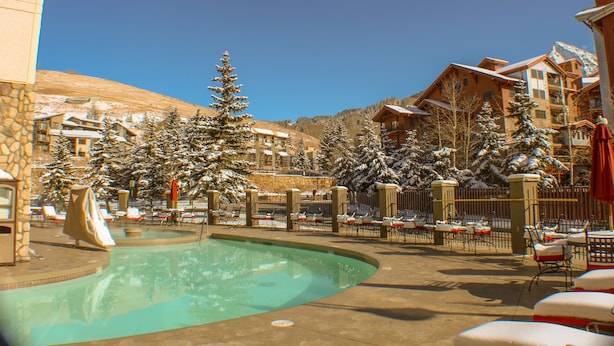 A resort with a swimming pool, snow-covered trees, and multiple buildings with balconies.