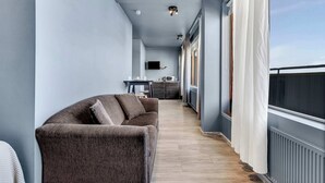 Een moderne woonkamer met een bank, een eethoek en een keuken op de achtergrond.