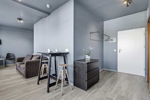 Un salon moderne comprenant un canapé, une petite table, un tabouret, un meuble et une porte.