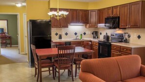 Una cocina compacta con armarios de madera, un refrigerador y un comedor con mesa y sillas.