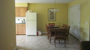 Un comedor con una mesa, sillas, un refrigerador y armarios de madera.