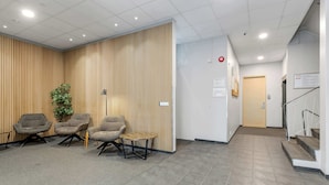 Een receptiegedeelte met een modern design, bestaande uit een receptiebalie, drie fauteuils, een klein rond tafeltje en een houten wandpaneel.