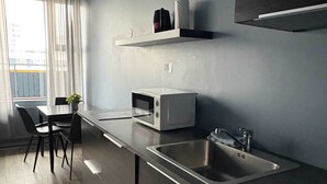 A modern kitchen with a microwave, sink, and a dining area with chairs and a table.