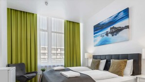 A hotel room with a bed, a desk, a chair, and a painting on the wall. - Iceland Comfort Apartments Double studio with view (Kópavogur)