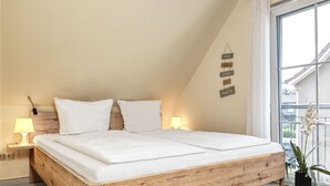 Een slaapkamer met een houten bed, twee nachtkastjes met lampen, een raam met uitzicht en een wanddecoratie.