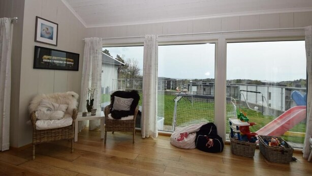 Amplia habitación con un gran ventanal corredero que da a un balcón con vista a un parque infantil.