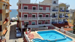 Un hotel de diversos pisos amb balcons, una piscina i vistes al mar.