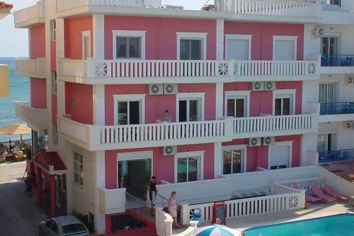 A multi-story hotel with balconies, a swimming pool, and a beach view.