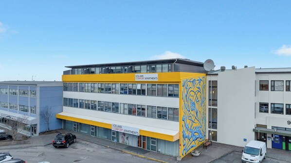 A multi-story building with a yellow and white facade, labeled 'ICELAND COMFORT APARTMENTS.'