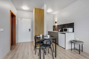 A modern kitchen with a microwave, kettle, and a small dining table with chairs. - Iceland Comfort Apartments Studio 3 Adults (Kópavogur)