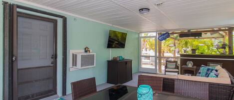 A covered patio area with a dining table, chairs, and a seating area.