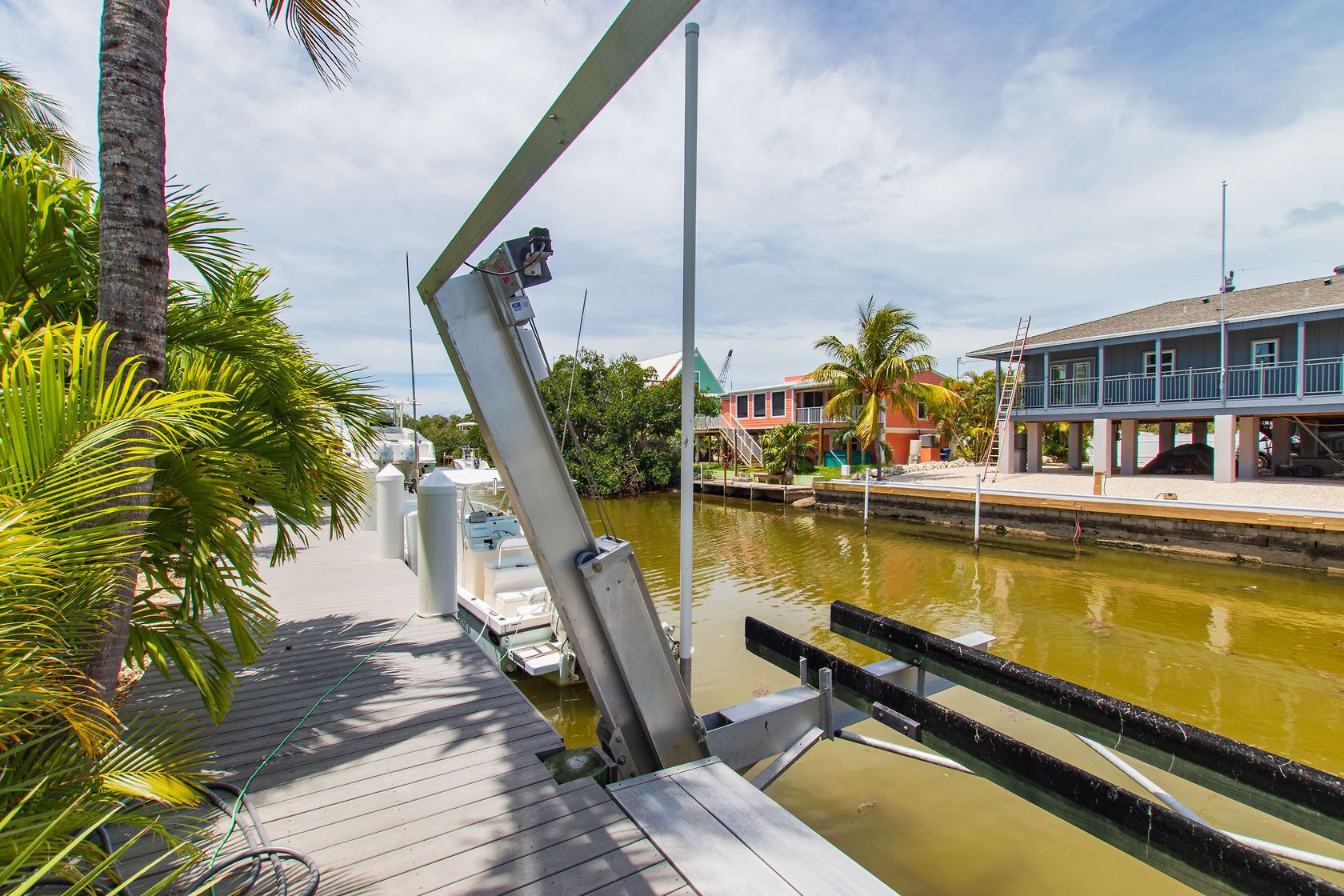 A dock with boats, a wooden walkway, and a building with balconies.