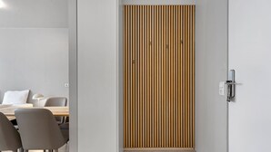 A modern interior with a wooden slat wall, a dining area with chairs and a table, and a light switch on the wall.