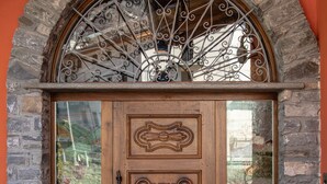 A wooden door with intricate carvings, set within a stone archway. - Wine-Farm La Source (Saint-Pierre)