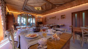 A dining area with wooden tables and chairs, a large dining table with plates, glasses, and a bowl of food. - Wine-Farm La Source (Saint-Pierre)
