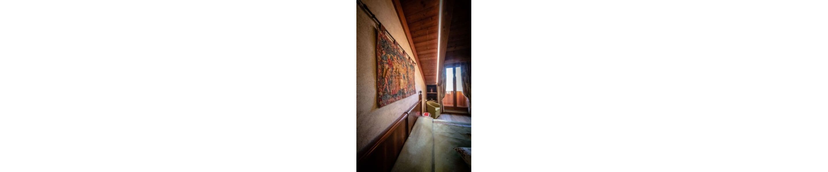 A corridor with a wooden ceiling and a tapestry on the wall.