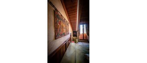 A corridor with a wooden ceiling and a tapestry on the wall.