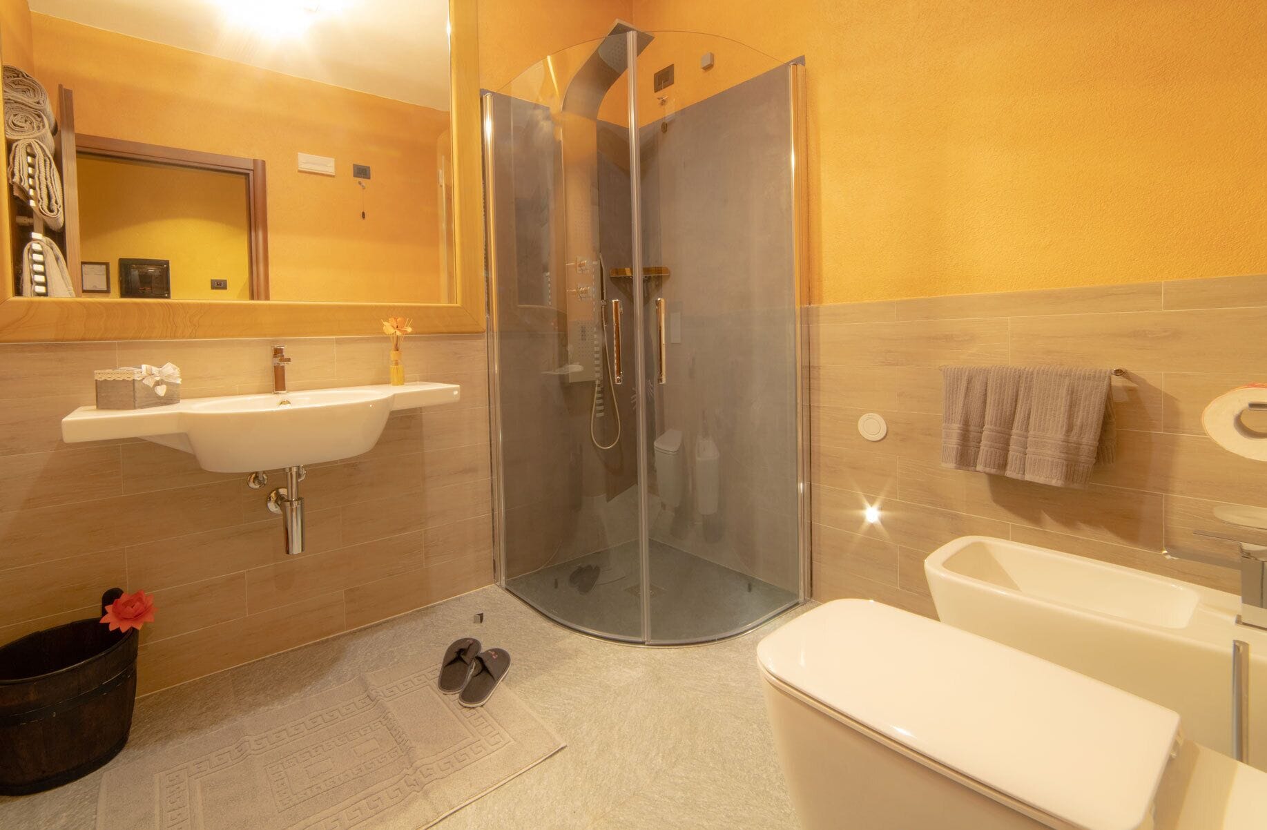 A modern bathroom with a glass-enclosed shower, a sink with a mirror, and a bathtub.