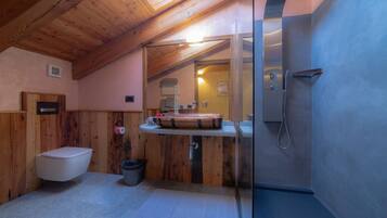 A compact bathroom with a wooden ceiling, a toilet, a sink with a wooden basin, and a shower.