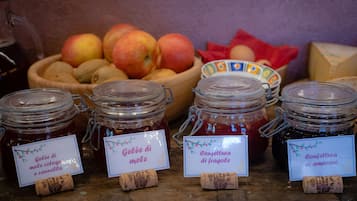 Frascos de conservas con etiquetas, un bol de frutas y una mesa de madera.