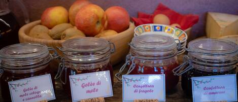 Frascos de conservas con etiquetas, un bol de frutas y una mesa de madera.