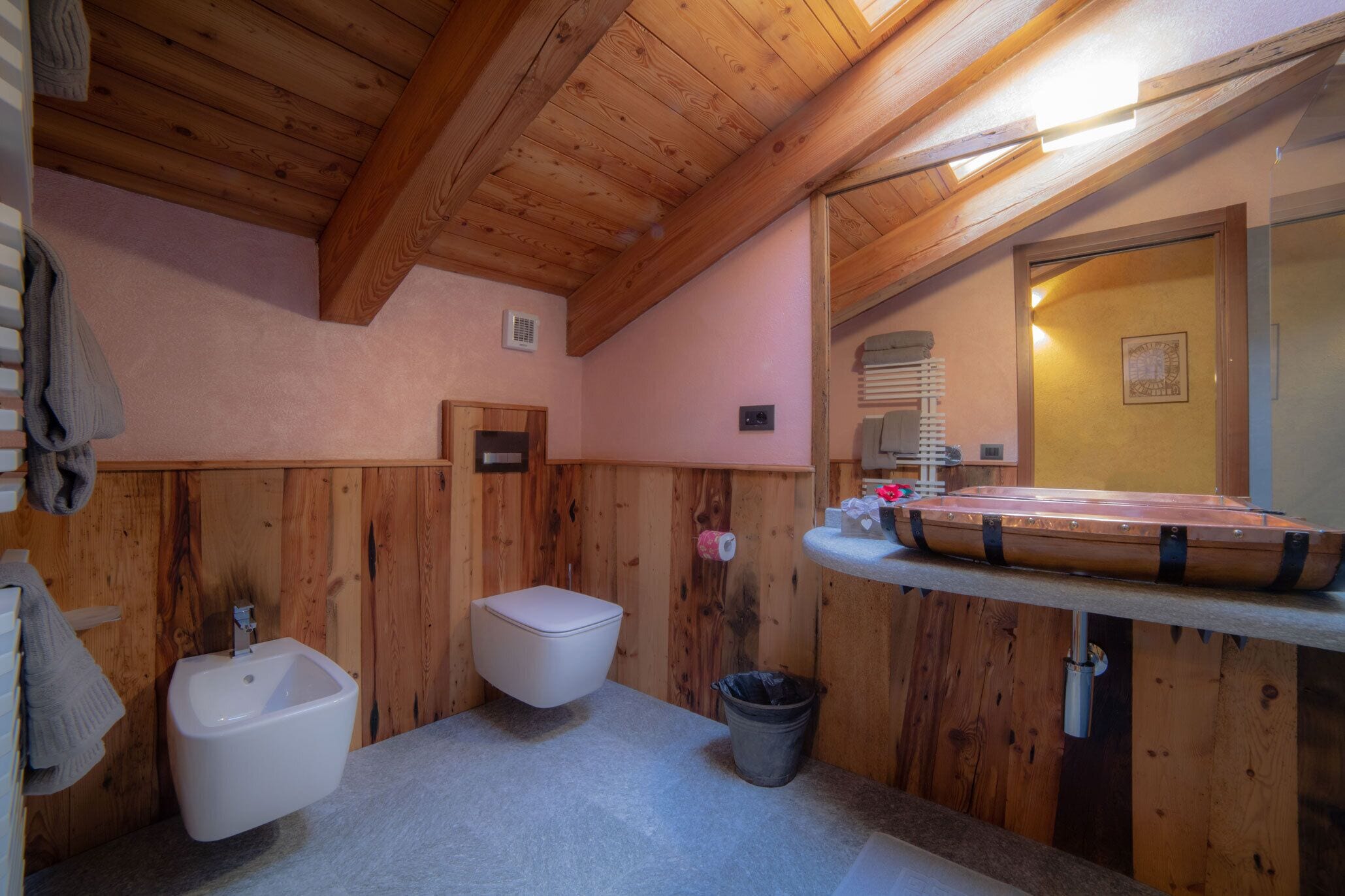A wooden bathroom with a bidet, toilet, and sink.