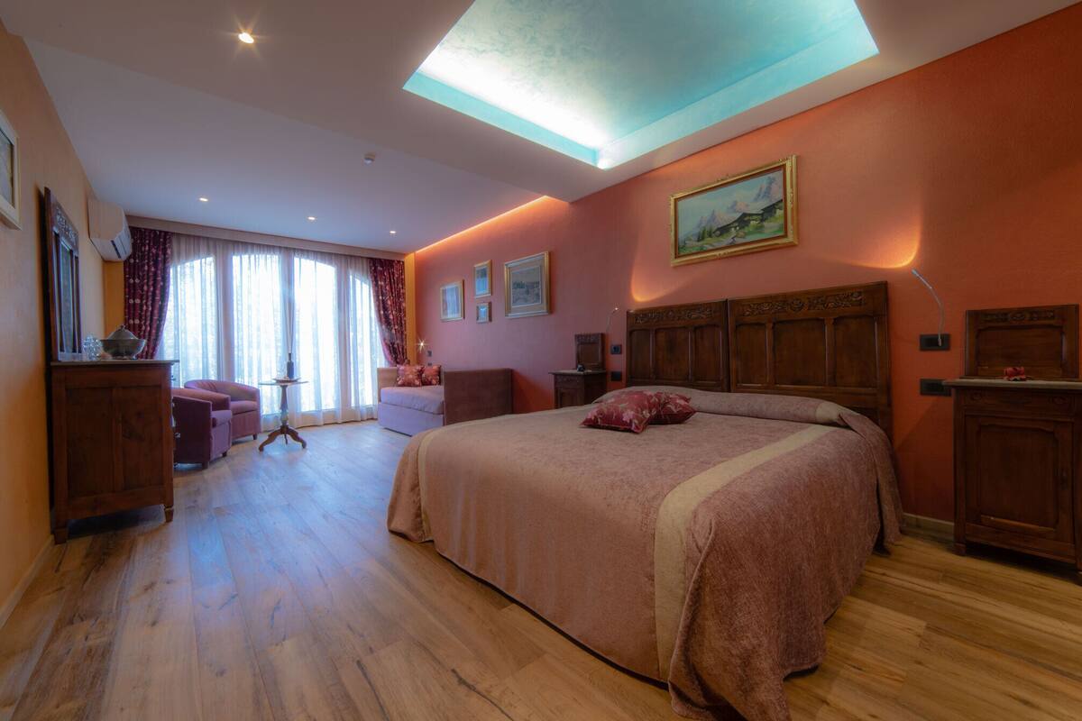 Ein Schlafzimmer mit einem großen Bett, einem Schreibtisch, einem Stuhl und einem Fenster mit Vorhängen.