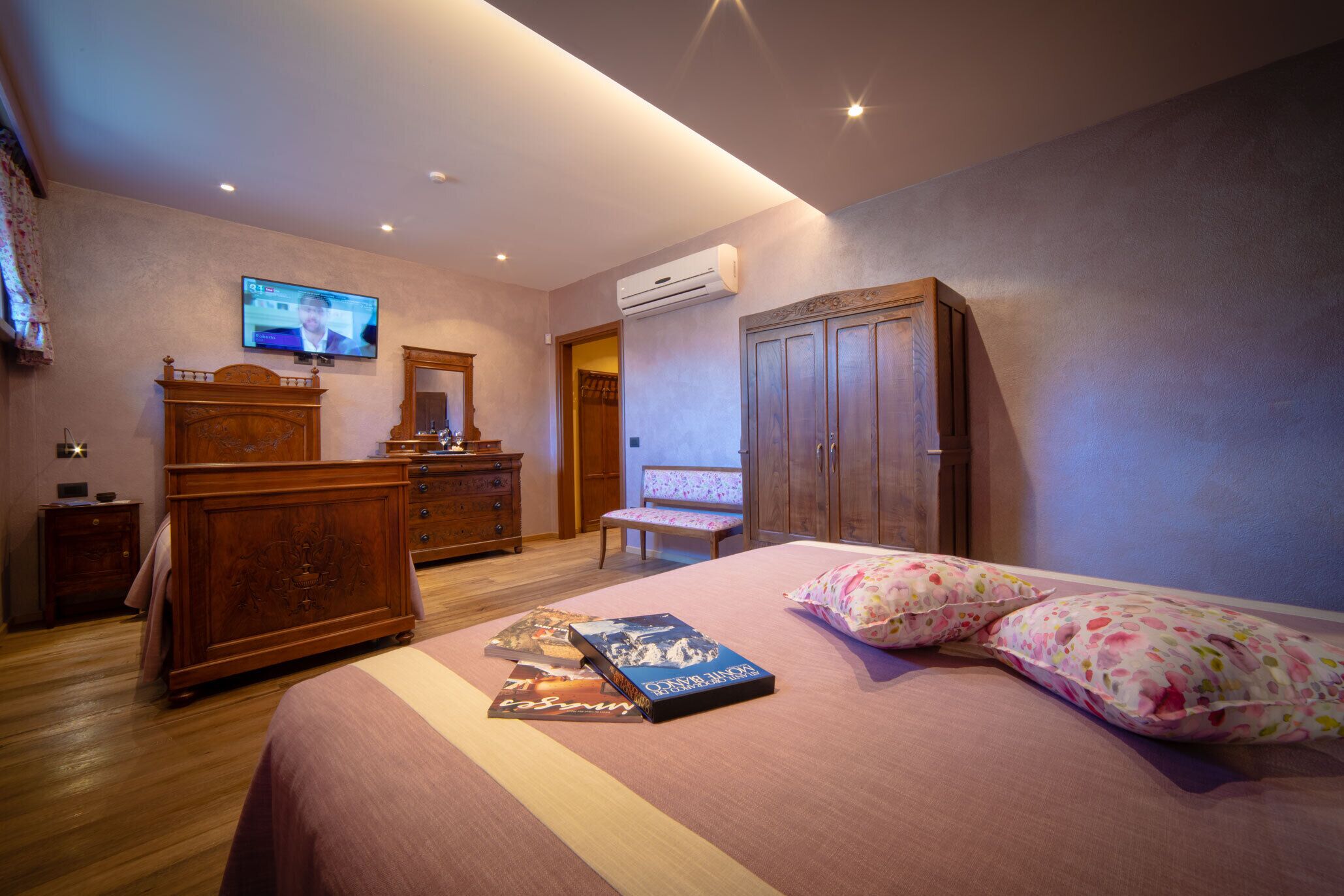 Une chambre à coucher comprenant un lit, une télévision, une armoire et un banc.