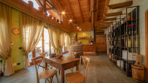 A rustic interior with a wooden dining table, chairs, and a wine rack. - Wine-Farm La Source (Saint-Pierre)