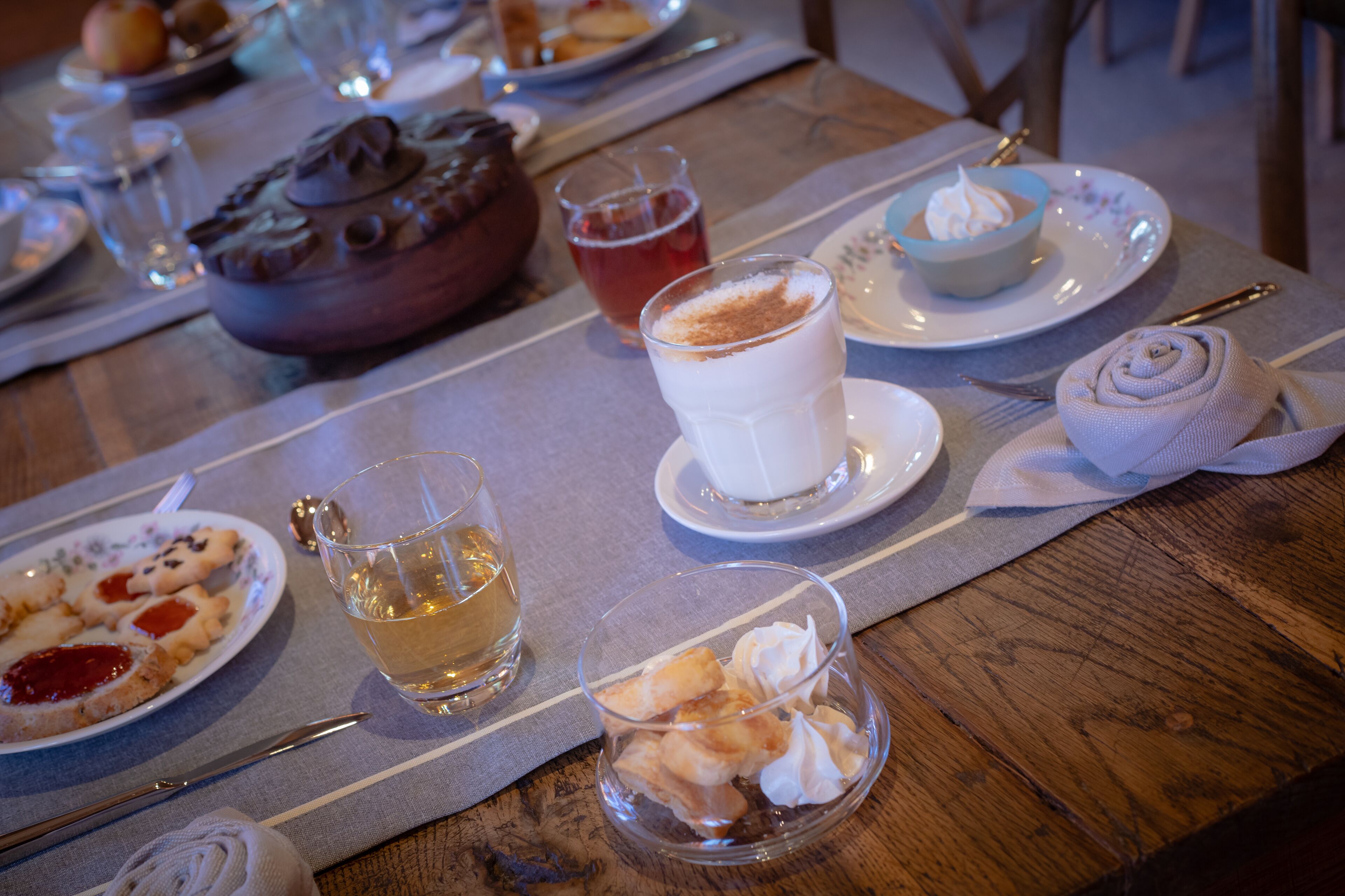 Una mesa de comedor con platos de comida, vasos de bebida y un bol de postre.